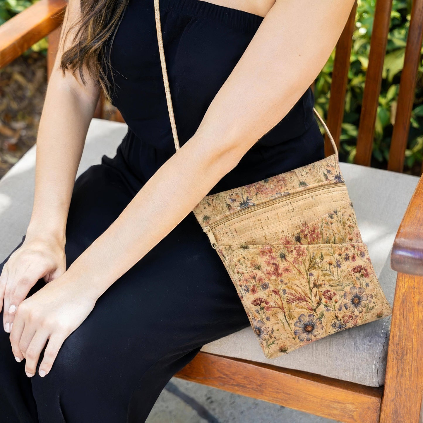 Person sitting outdoors with a floral-patterned crossbody bag