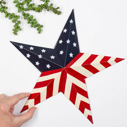 Decorative star with American flag design held by a hand on a white background with greenery