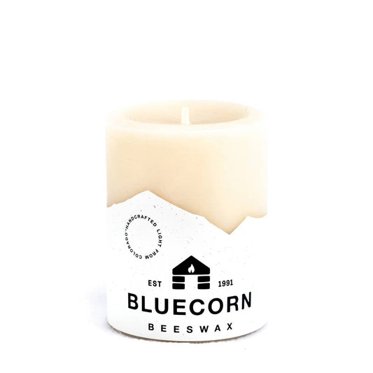 White candle with Bluecorn Beeswax logo on a white background