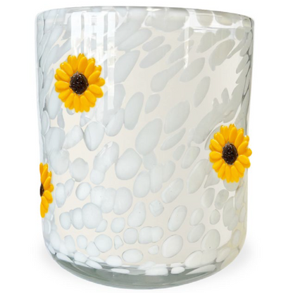 Glass candle with textured white surface and yellow sunflower designs on a white background