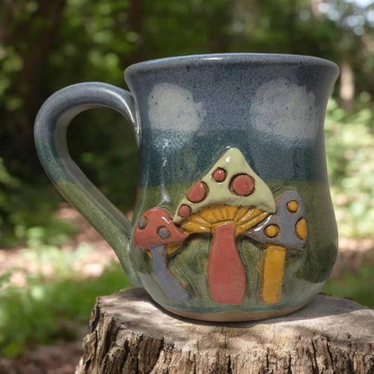 Ceramic mug with mushroom design on a wooden stump outdoors