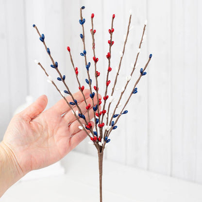 Hand holding a decorative branche with red, blue, and white berries on a white background