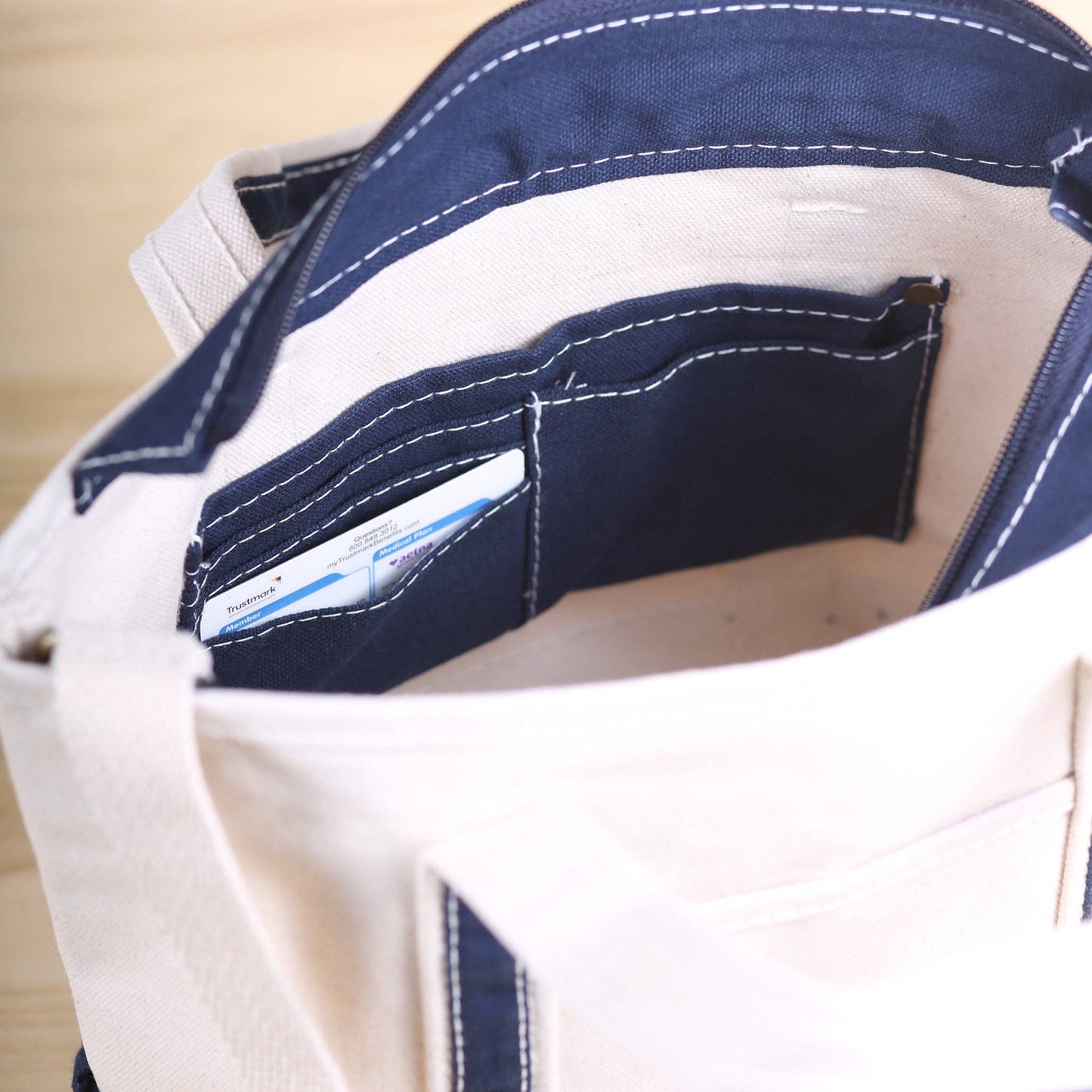 Close-up of a white bag with a blue accent pocket, showing a card inside.