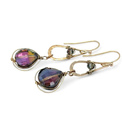 Gold earrings with purple heart-shaped stones on a white background