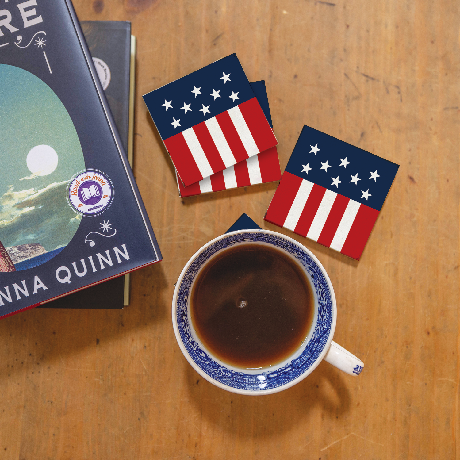 Cup of coffee with American flag coasters and a book on a wooden surface