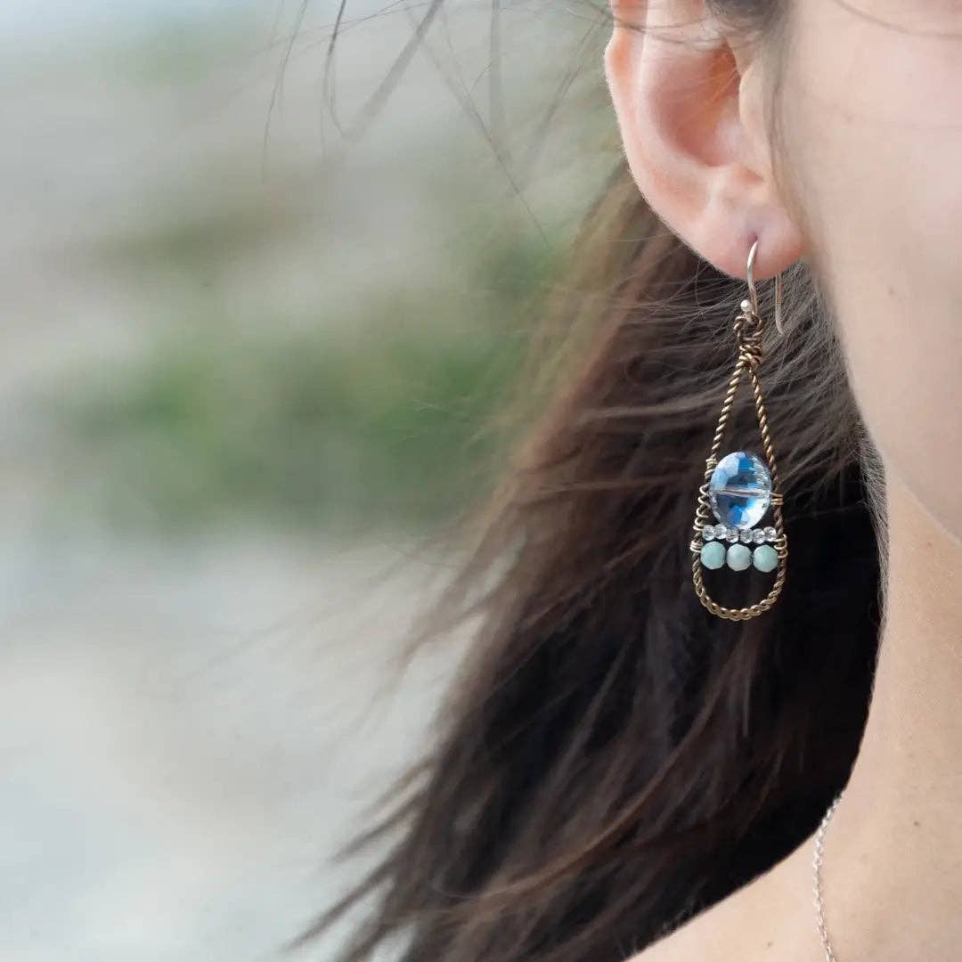 Close-up of a person wearing a decorative earring with a blurred natural background