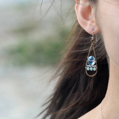 Close-up of a person wearing a decorative earring with a blurred natural background