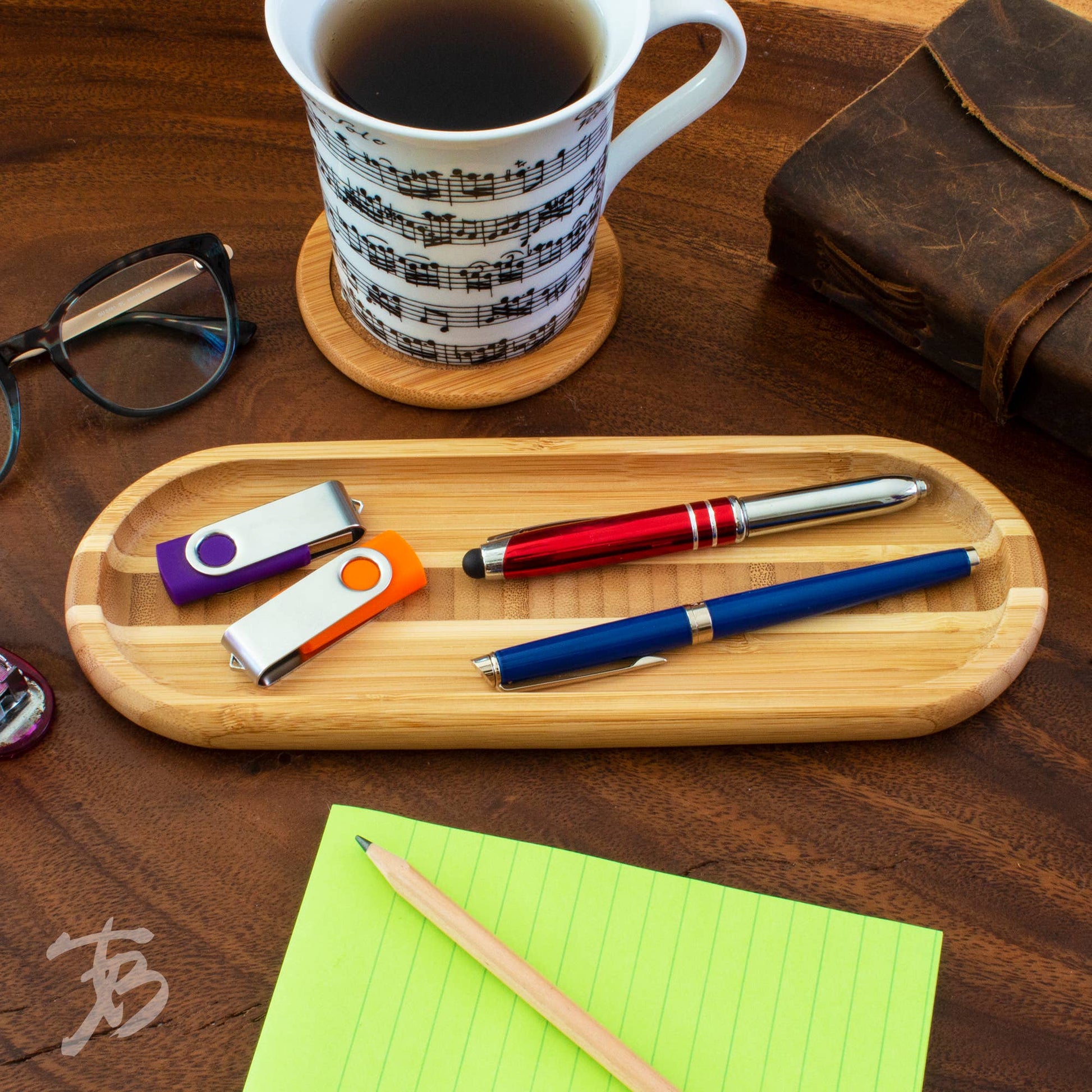 Wooden tray with pens, USB drives, and a mug on a wooden surface