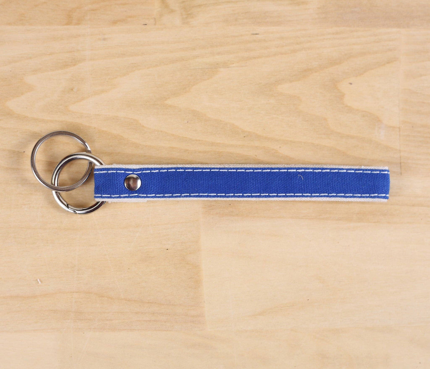 Blue keychain with two rings on a wooden surface