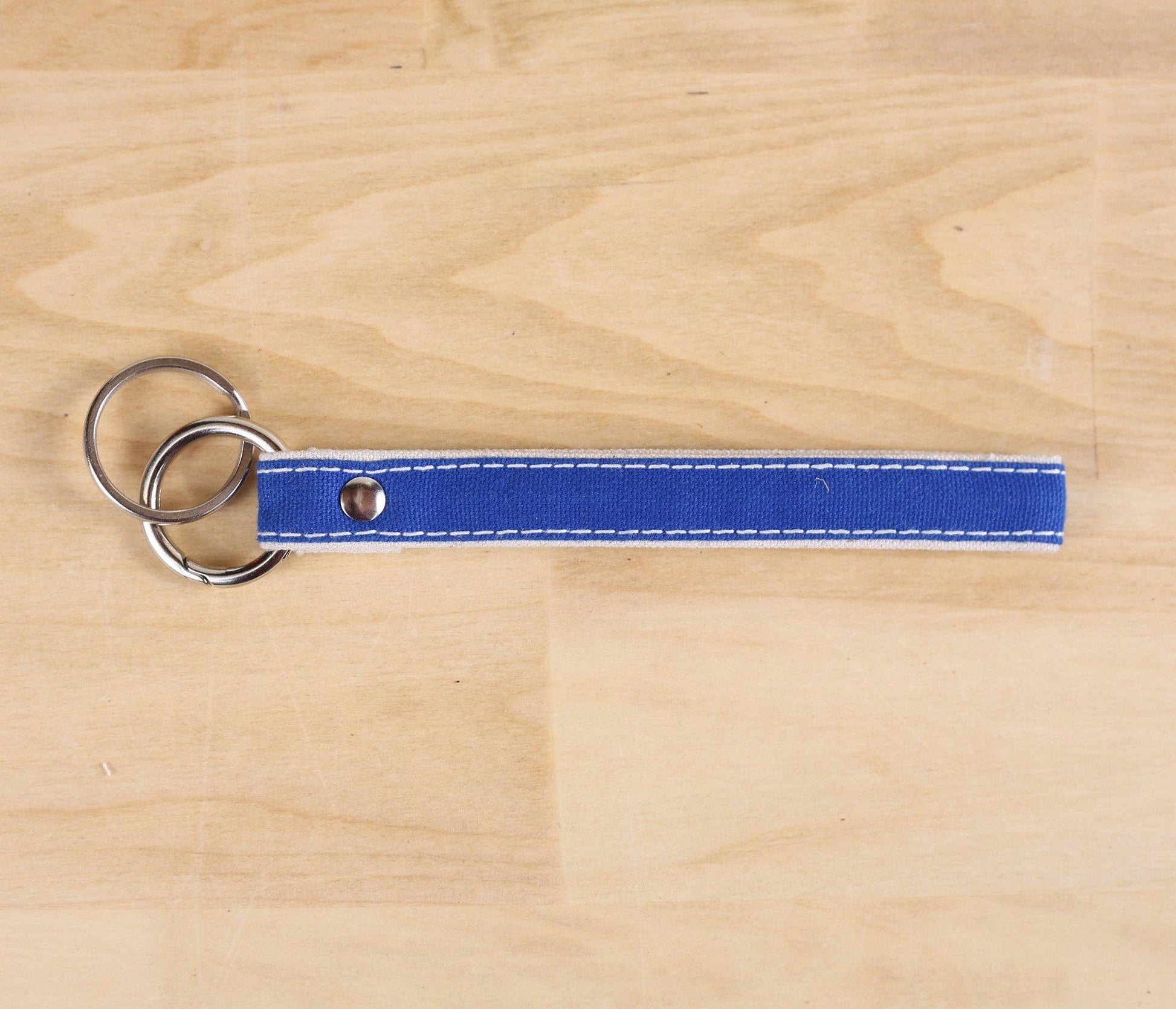 Blue keychain with two rings on a wooden surface