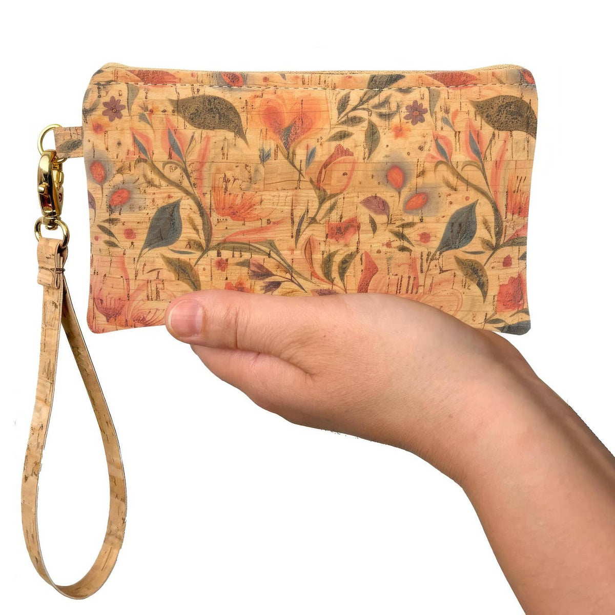 Hand holding a floral-patterned cork wristlet with a gold strap on a white background