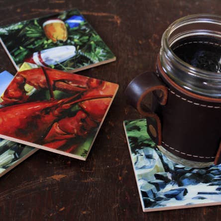 Coasters with artistic designs on a wooden surface with a mug.