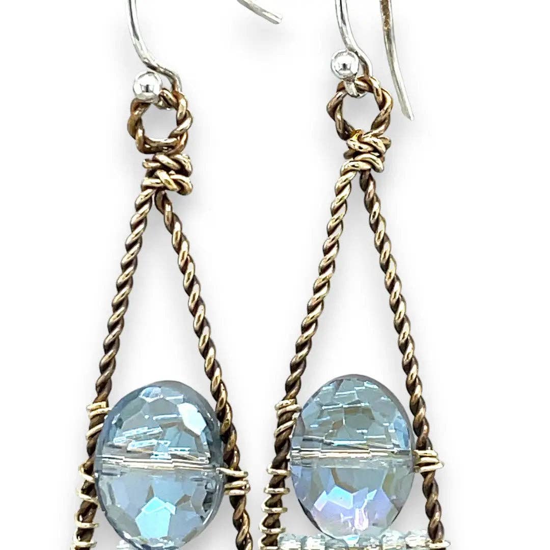 Pair of earrings with blue beads and braided gold and silver wires on a white background