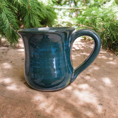Blue ceramic mug on a wooden surface with greenery in the background