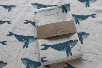 Folded towel with whale design and 'The High Fiber' label on a matching patterned background