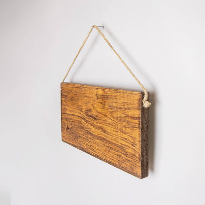 Wooden sign with rope hanging on a white wall