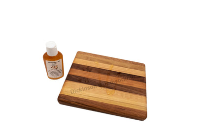 Wooden cutting board with a bottle of Dickinson's Kitchenware Oil Finish on a white background.
