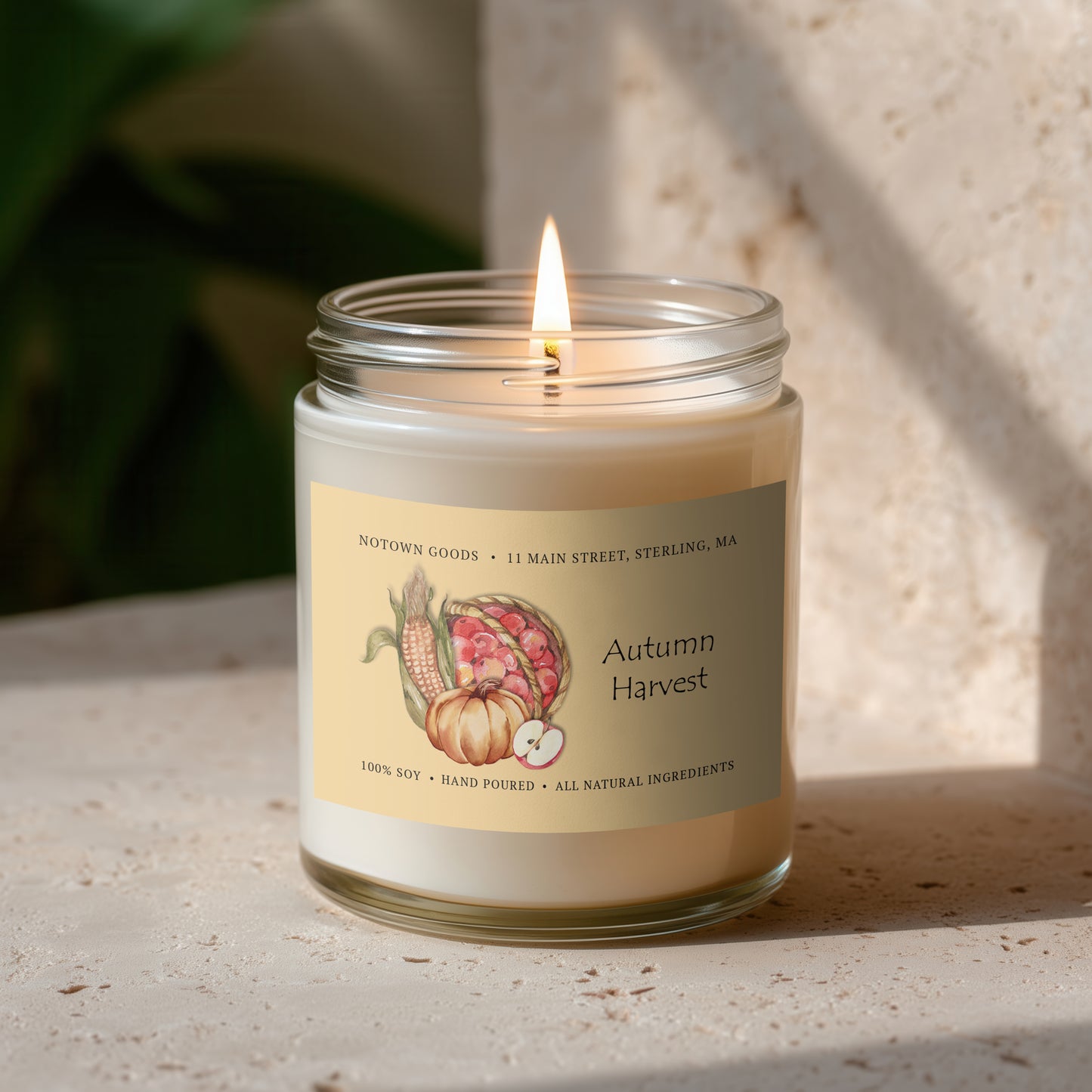 Clear jar candle with white wax and a decorative label on a textured outdoor background.