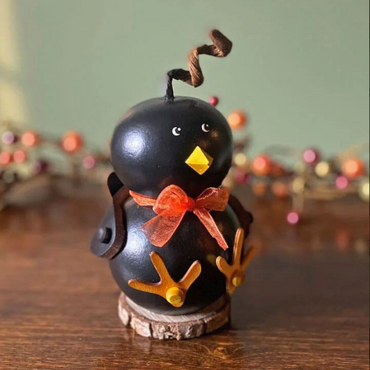Decorative black bird figurine with an orange bow on a wooden surface