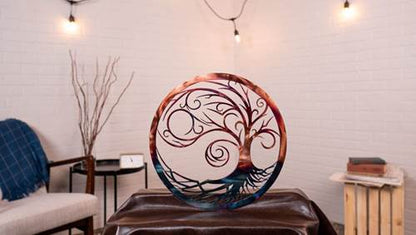 Decorative metal tree of life sculpture on a table in a room with a couch and lamp.