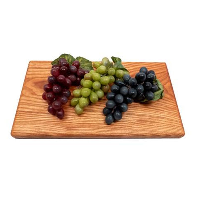 Wooden cutting board with red, green, and black grapes on a white background