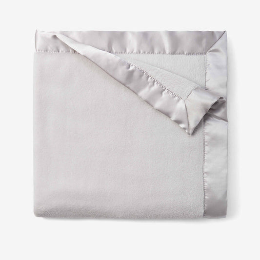 Folded blanket with satin edge on a  plain background