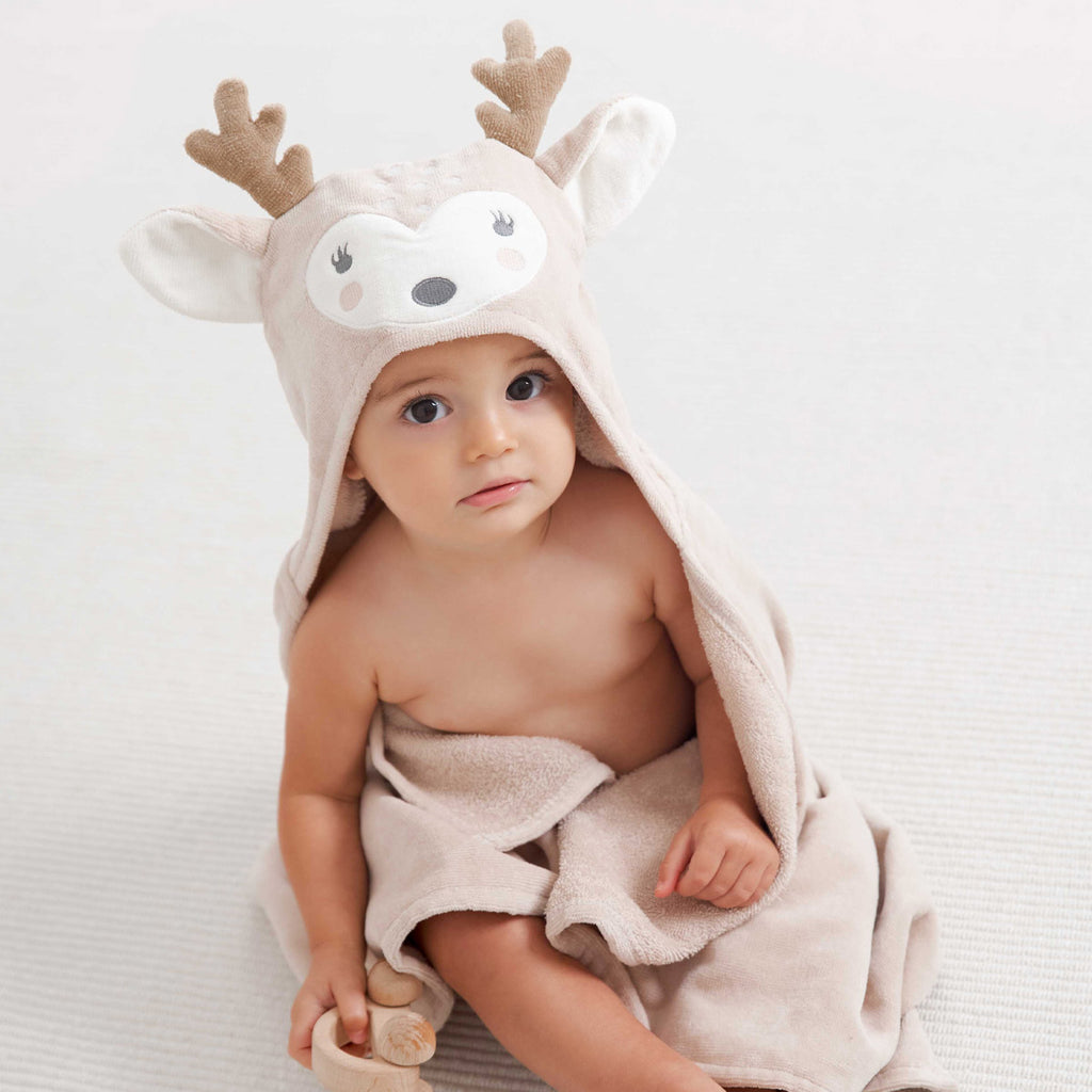 Baby wearing a hooded towel with deer design on a white background