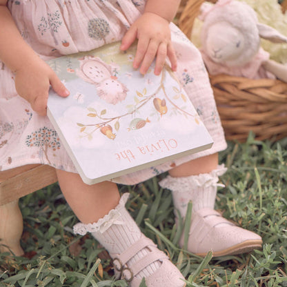 Child holding a book with animal illustrations on grass