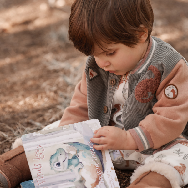 Child reading a book outdoors with a natural background