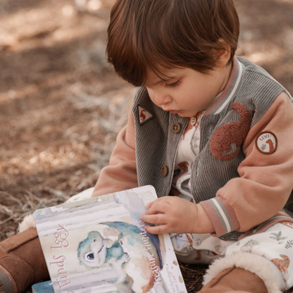Child reading a book outdoors with a natural background