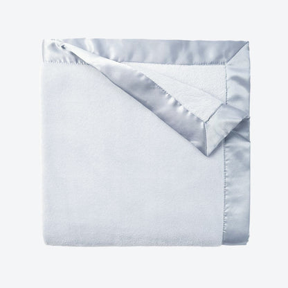 Folded light blue blanket with silver satin trim on a white background