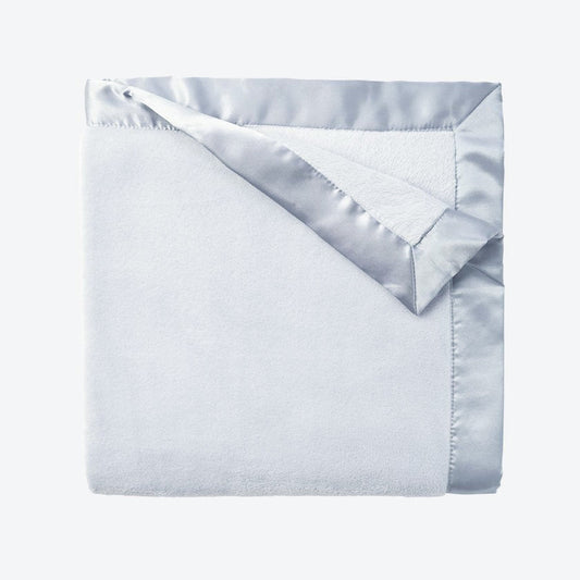 Folded light blue blanket with silver satin trim on a white background
