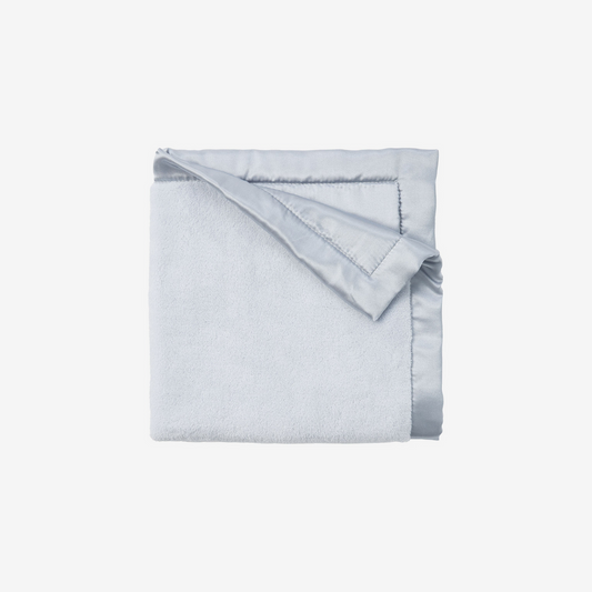 Folded light blue blanket on a white background