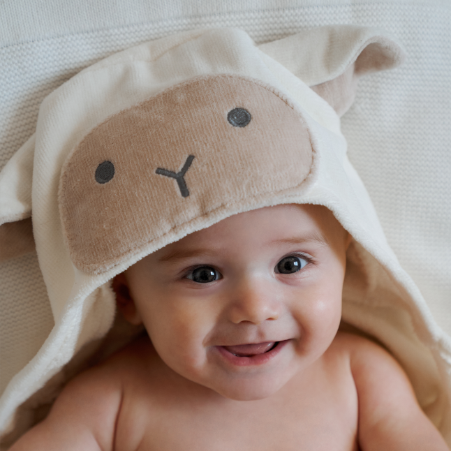 Baby wearing a soft, beige sheep hooded towel