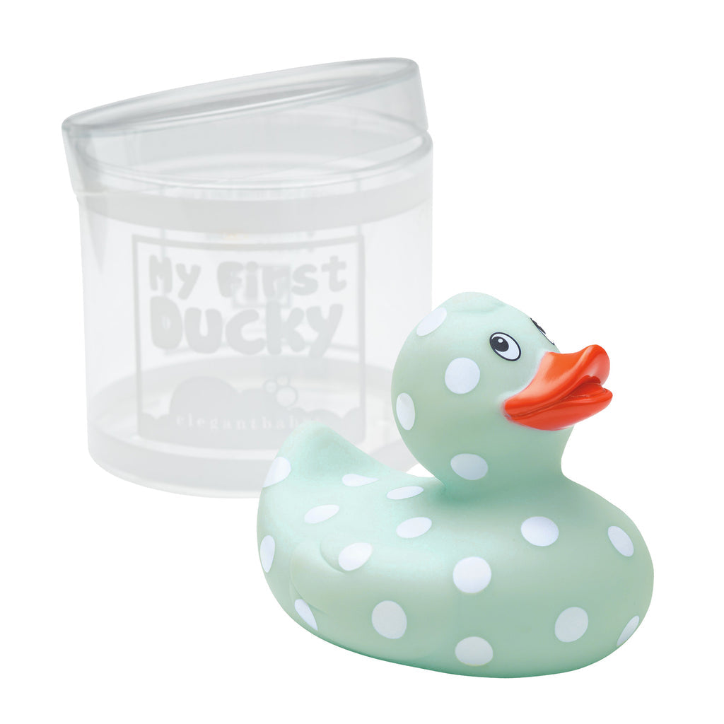 Light blue rubber duck with white polka dots and orange beak next to a clear container labeled 'My First Duckie' on a white background.