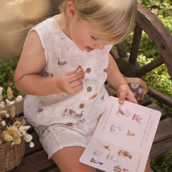 Child in a patterned outfit reading a book outdoors