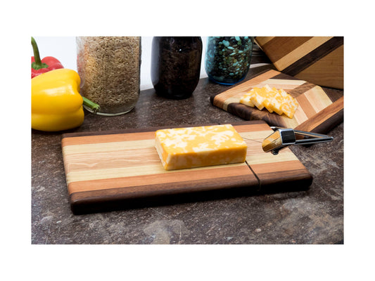 Wooden cheese slicing cutting board with cheese and a knife on a kitchen counter.