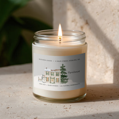 Clear jar candle with white wax and a decorative label on a blurred outdoor background.