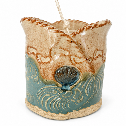 Ceramic candle holder with wave design and shell detail on a white background