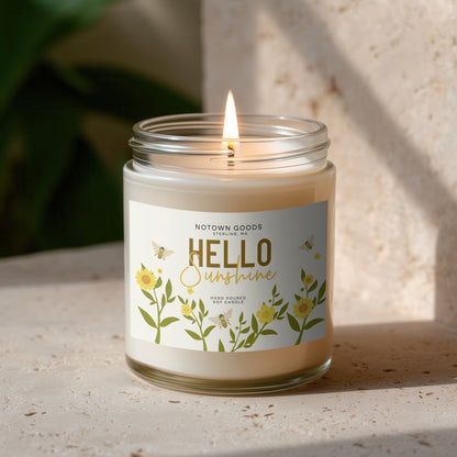 Clear jar candle with white wax and a decorative label on a blurred outdoor background.