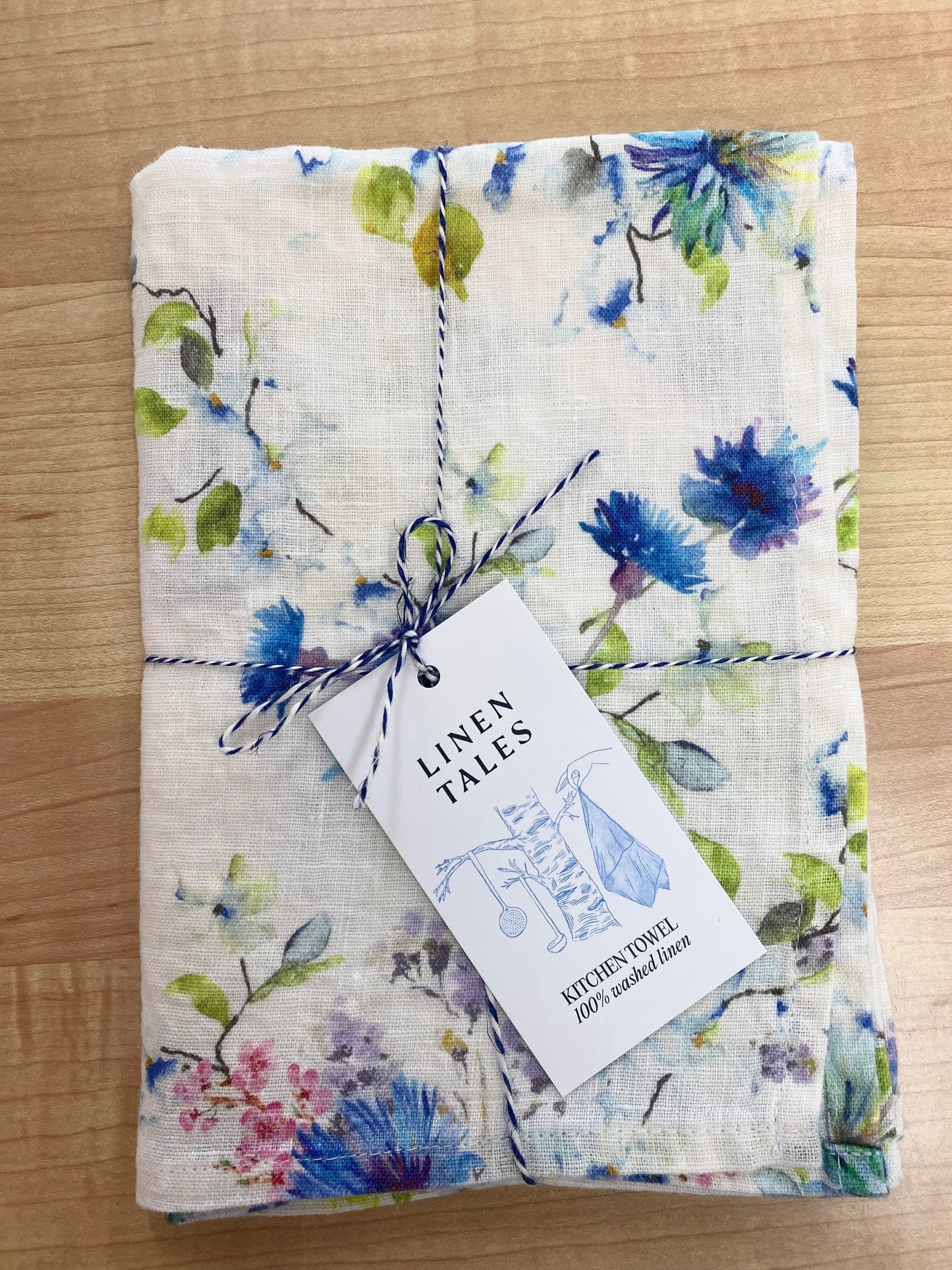 Floral patterned tea towel on wooden background.