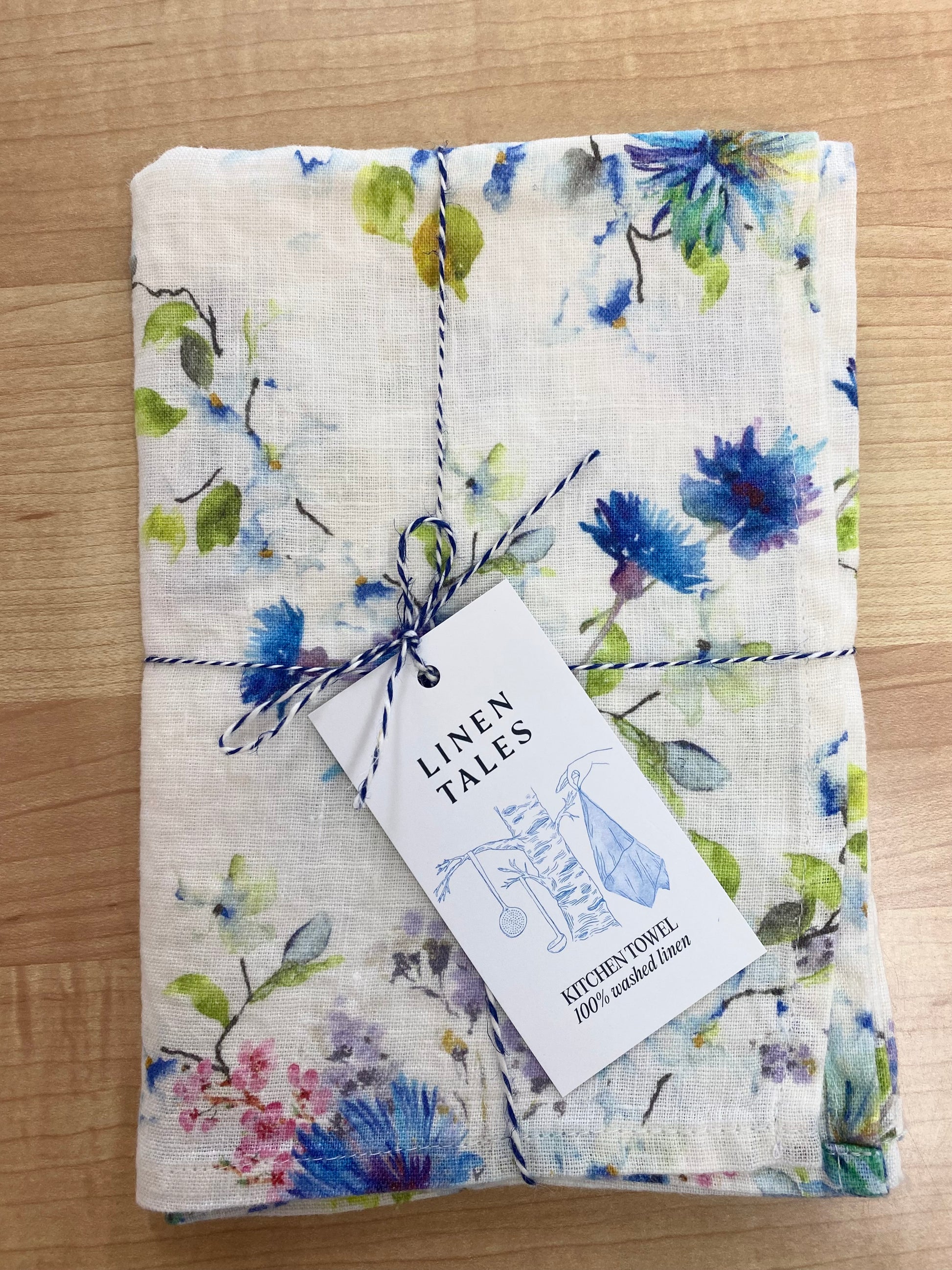 Floral patterned tea towel on wooden background.