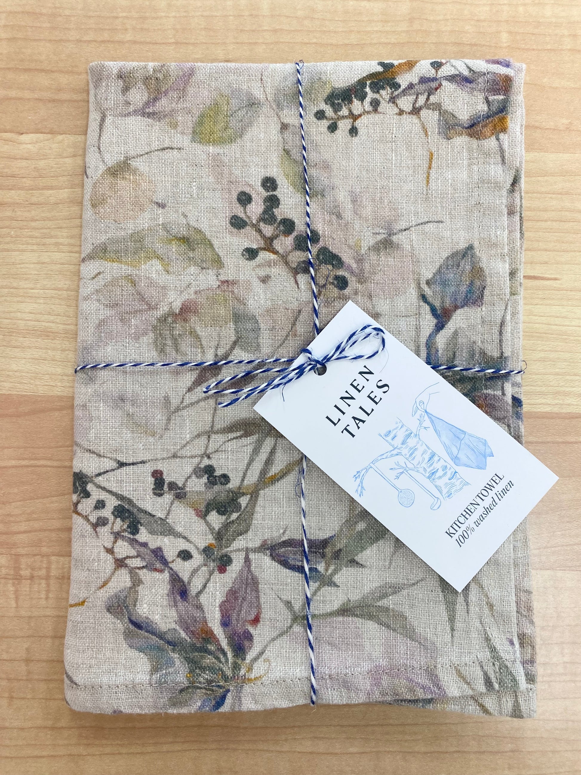 Floral patterned tea towel on wooden background.