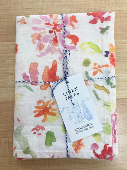 Floral patterned tea towel on wooden background.