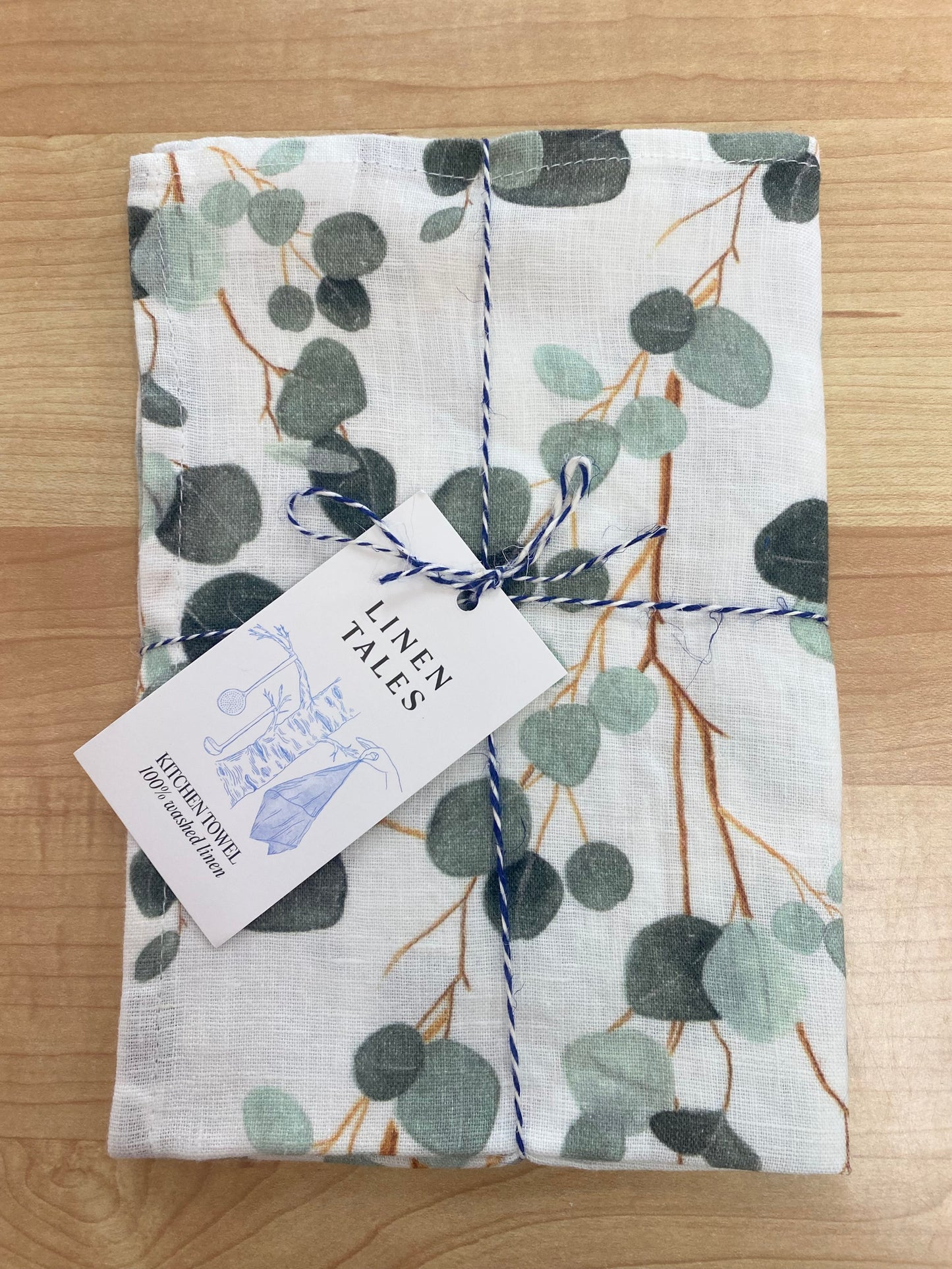 Leaves patterned tea towel on wooden background.