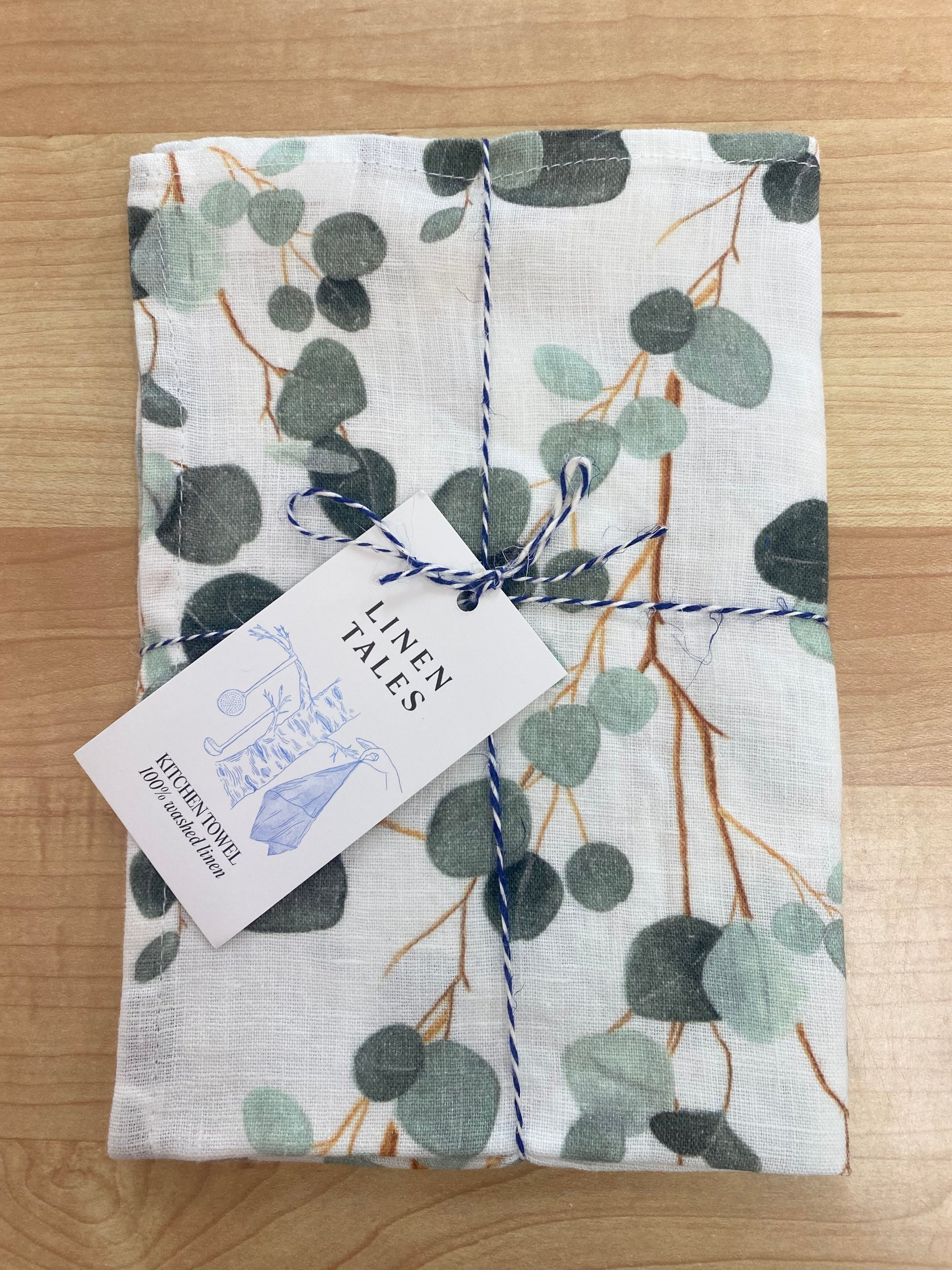 Leaves patterned tea towel on wooden background.