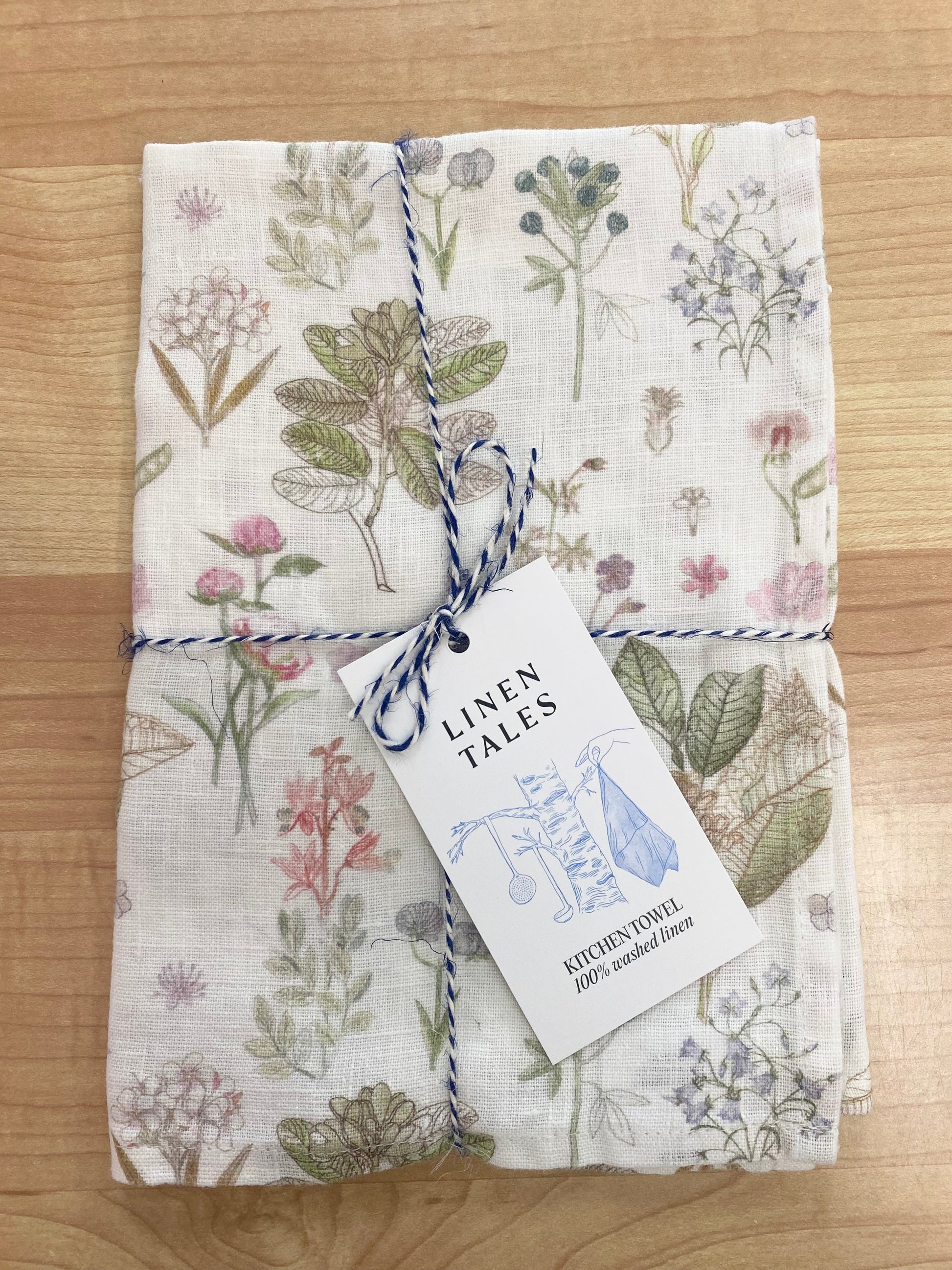 Floral patterned tea towel on wooden background.
