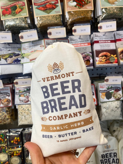 Bag of Vermont Beer Bread Company Garlic Herb beer bread held in front of a store shelf with various food items.
