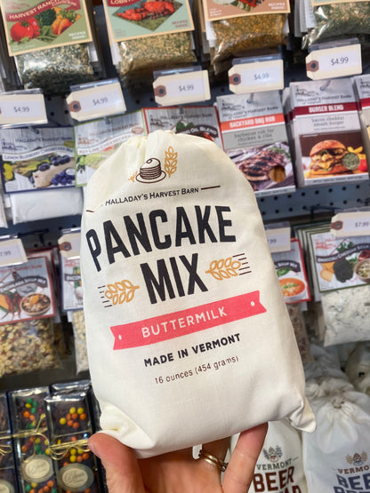 Hand holding a package of Halladay's Pancake Mix in a store setting