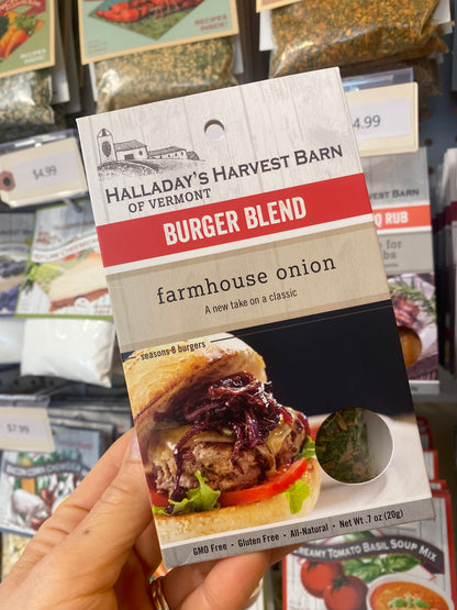 Hand holding a package of Halladay's Harvest Barn Burger Blend farmhouse onion seasoning mix.